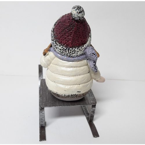 Decoratief beeldje meisje op slee in winter kleding